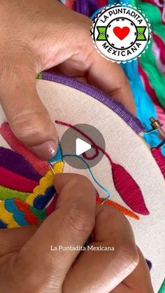 a person is stitching something on a colorful piece of cloth with scissors and thread