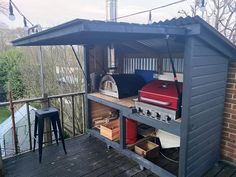 an outdoor bbq on a deck next to a brick wall and wooden flooring