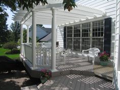 a white porch with chairs and potted plants