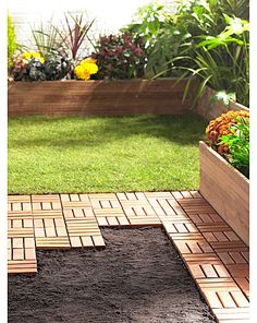 a wooden planter sitting on top of a grass covered ground next to a garden