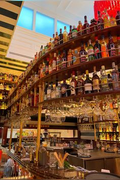 a bar filled with lots of bottles and glasses next to a spiral shelf full of liquor