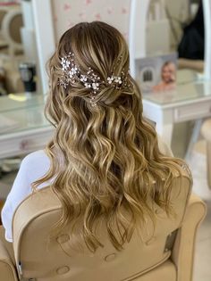 the back of a woman's head with long hair and flowers in her hair