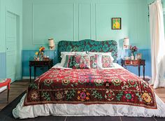 a bedroom with blue walls and red bedspread, two chairs, and a bed in the middle