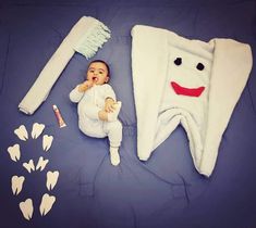 a baby laying on top of a bed next to a toothbrush and dental floss