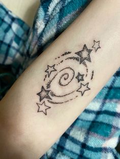 a woman's arm with stars and a spiral design on it, in black ink