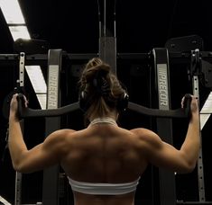 a woman with headphones on working out in a gym setting, looking back at the camera