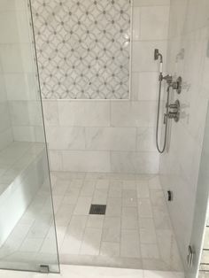 a walk in shower sitting next to a white tiled wall and floor with glass doors