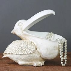 a white ceramic bird with pearls on it's tail and its wings spread out