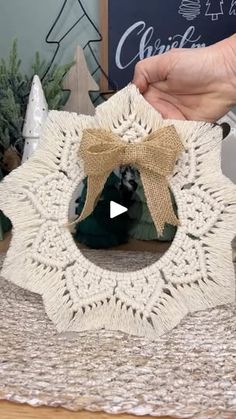 someone is holding up a crocheted doily with a bow on it