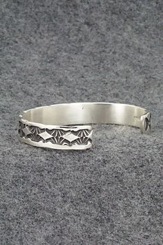 This sterling silver bracelet was made by Navajo silversmith Elvira Bill. The inside is signed Elvira Bill and stamped sterling.Size: 5 7/8" (will fit up to a 7 3/8" wrist)Gap: 1 1/2"Width: 3/8"Free shipping on all orders! We ship with USPS and always include tracking. All orders ship within a day of payment.Returns are accepted up to 30 days after you receive your order. Just send us a message. Our shop offers cash back or store credit. The item must be returned in new condition. Antique Silver Sterling Silver Bangle Bracelet, Collectible Sterling Silver Bracelets With Oxidized Finish, Oxidized Sterling Silver Southwestern Bracelet, Oxidized Finish Southwestern Sterling Silver Bracelet, Unique Antique Silver Sterling Silver Bracelet, Artisan Sterling Silver Bracelet With Oyster Detail, Artisan Sterling Silver Oyster Bracelet, Artisan Sterling Silver Cuff Bracelet With Engraving, Artisan Engraved Sterling Silver Cuff Bracelet