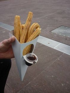 a person holding up a paper container filled with french fries