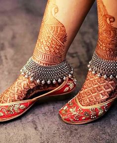 the legs and feet of a woman with henna tattoos on their ankles, wearing red shoes