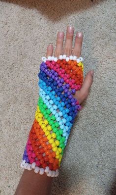 a child's hand is covered in multicolored beads and has a knitted wristband