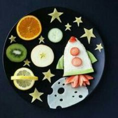 a black plate topped with fruit and vegetables on top of a blue tablecloth covered in stars