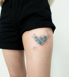 a woman with a tattoo on her thigh showing the back side of her leg, which is made up of small blue squares