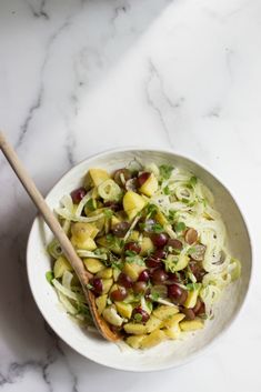 a white bowl filled with pasta and olives on top of a marble countertop