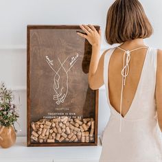 a woman standing in front of a sign with wine corks on the bottom and back