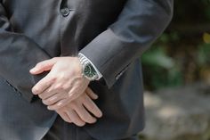 a close up of a person wearing a watch on their wrist and holding his hand in his pocket