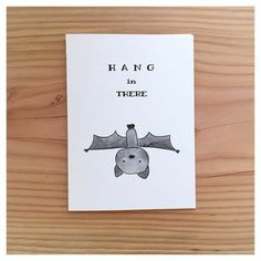 a card with an image of a bat hanging from it's side on a wooden surface