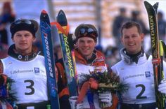 three men holding up their skis in front of the camera