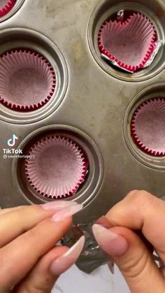 a hand holding a cupcake with pink icing and sprinkles on it