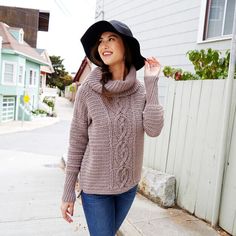 a woman walking down the street wearing a hat and sweater