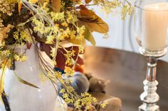 a vase filled with yellow flowers next to a candle on top of a wooden table