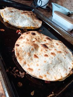 two pita breads sitting on top of an oven pan next to each other