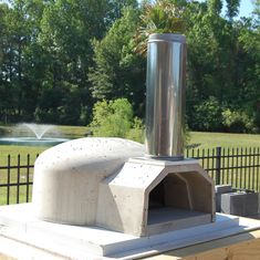 an outdoor pizza oven with a water fountain in the background