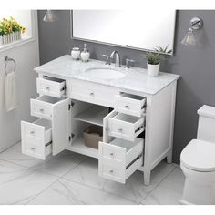 a bathroom vanity with two drawers and a mirror above it, next to a toilet