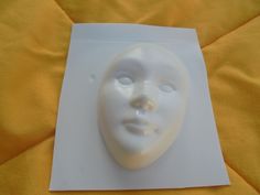 a white plastic mask on top of a yellow sheet