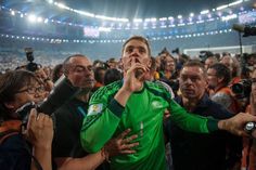 a man in a green shirt is surrounded by people at a soccer game with cameras around him