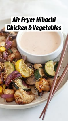 a white plate topped with chicken and veggies next to a bowl of dipping sauce