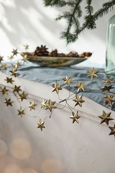 gold stars are hanging from the ceiling next to a glass vase and plate on a table