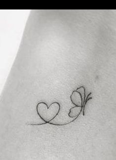 a small tattoo with two hearts on the back of the arm, and an arrow in the middle