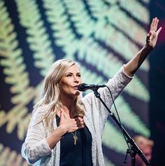 a woman standing in front of a microphone and holding her hand up to the air