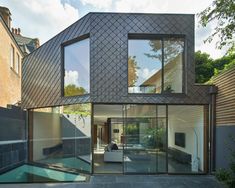 a modern house with glass walls and sliding doors on the outside, surrounded by brick buildings