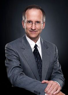 a man in a suit and tie posing for a photo with his arms folded out