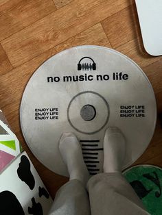 a person standing on top of a wooden floor next to a white disk that says no music no life