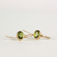 Minimalist and chic gold drop earrings with green Peridot, handmade of yellow 14k solid gold. The dazzling yellowish green Peridot gemstone is faceted, and is set in a bezel with an open back so light comes through the stone enhancing its color and beauty. These unique modern earrings are eye catching, and will add an elegant touch to your appearance. Silicone ear cups are included for safety. Total length of the earrings: ~ 32 mm 1.2 inch) Size of the stones: 7x9 mm * The earrings will be packe Everyday Green 14k Gold Earrings, Minimalist Yellow Gold Earrings For May Birthstone, Minimalist Yellow Gold May Birthstone Earrings, Elegant Peridot Earrings With Ear Wire, 14k Gold Green Earrings With Ear Wire, Elegant Peridot Dangle Earrings, Elegant Peridot Birthstone Earrings, Yellow Gold Peridot Earrings For Gift, Elegant Oval Peridot Earrings