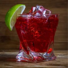 a close up of a drink in a glass with a lime slice on the rim