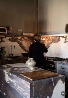 a man standing in a kitchen next to a counter top with a vase on it