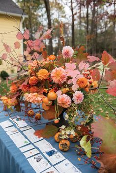 an arrangement of flowers on a table in the middle of a yard with blue cloth