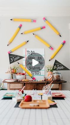 there are many pencils hanging on the wall above a table with an apple and crayons