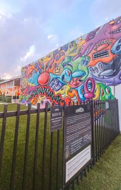 a large colorful mural on the side of a building next to a black metal fence