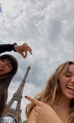 two girls pointing at the eiffel tower in paris, france with their fingers pointed up