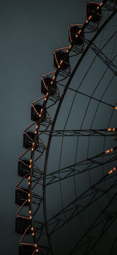 the ferris wheel is lit up at night with many lights on it's sides