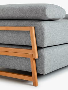 a grey couch with wooden legs and arm rest