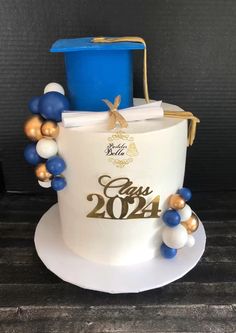 a white cake with blue and gold decorations on it's side, in the shape of a bucket