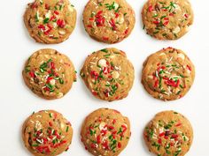 twelve cookies with sprinkles and nuts arranged in a circle on a white surface